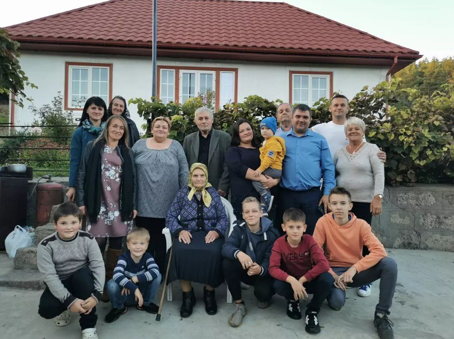 На фото: уся родина біля відновленої хати.